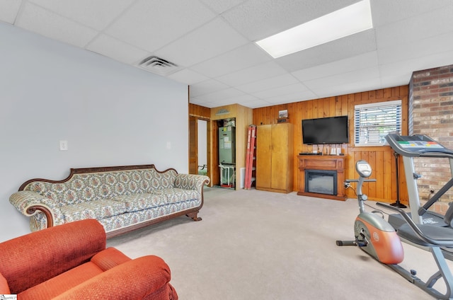 carpeted living room featuring a paneled ceiling and wooden walls