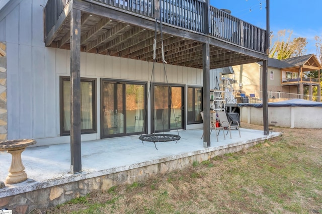 rear view of property with a patio, a covered pool, and a yard