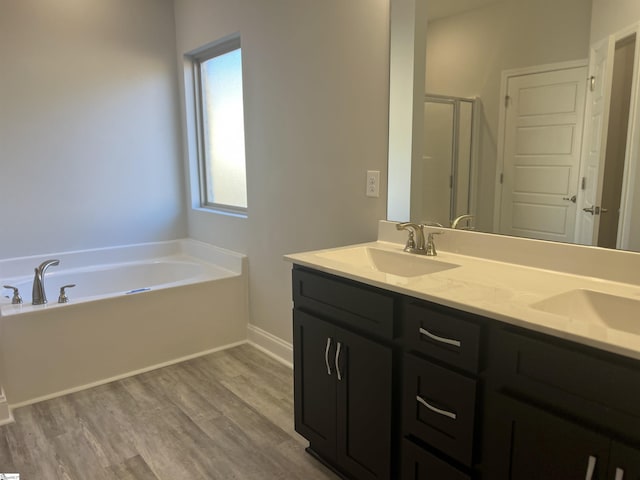 bathroom with wood-type flooring, shower with separate bathtub, and vanity