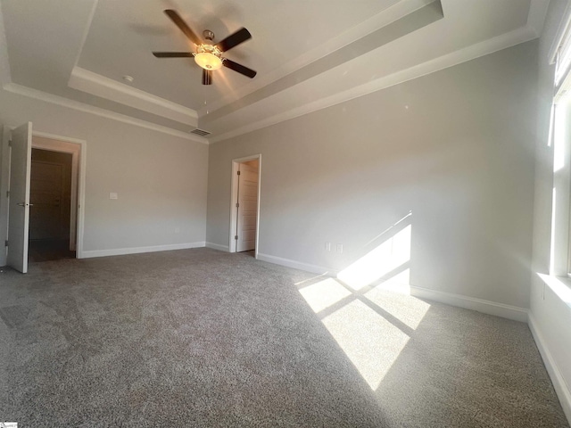 spare room with ceiling fan, a tray ceiling, and carpet floors