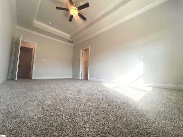 carpeted empty room with a raised ceiling and ceiling fan