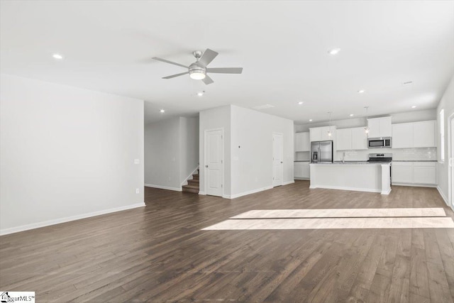 unfurnished living room with light wood finished floors, baseboards, a ceiling fan, stairway, and recessed lighting