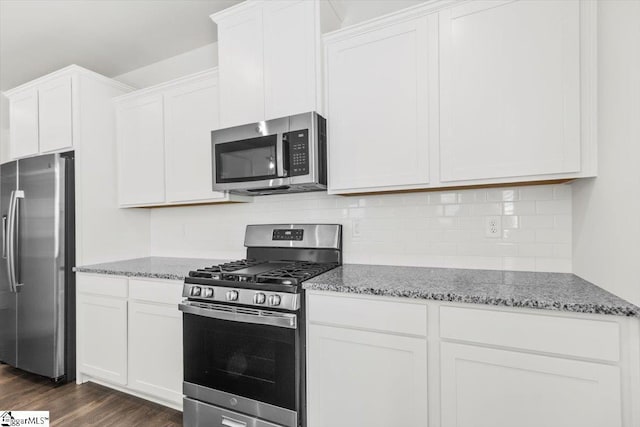 kitchen with stainless steel appliances, stone countertops, dark wood-style flooring, and white cabinetry