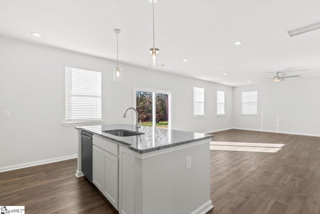 kitchen featuring a sink, visible vents, open floor plan, hanging light fixtures, and an island with sink