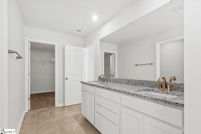 bathroom with double vanity, visible vents, and a sink