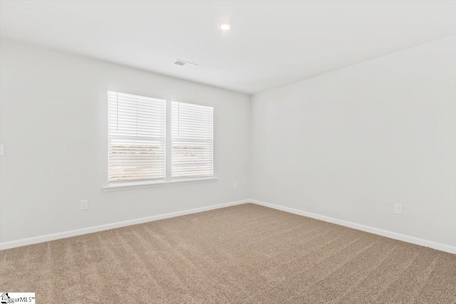 empty room featuring carpet floors, visible vents, and baseboards