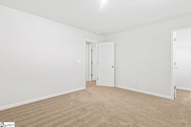 empty room featuring light carpet and baseboards