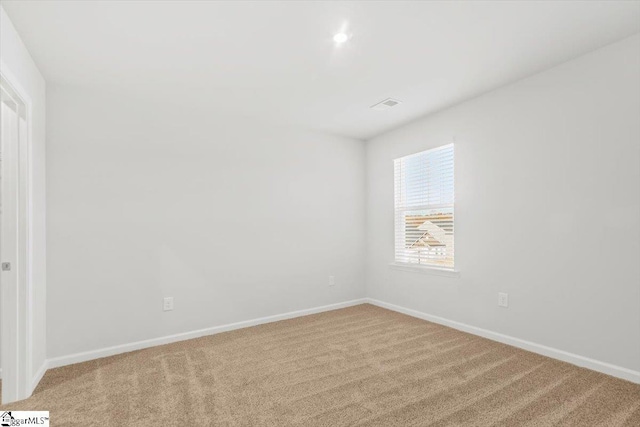 spare room featuring carpet, visible vents, and baseboards