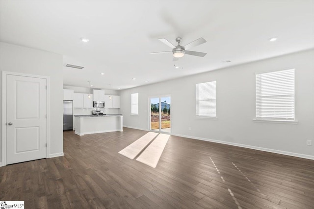 unfurnished living room featuring ceiling fan, dark wood-type flooring, recessed lighting, and baseboards