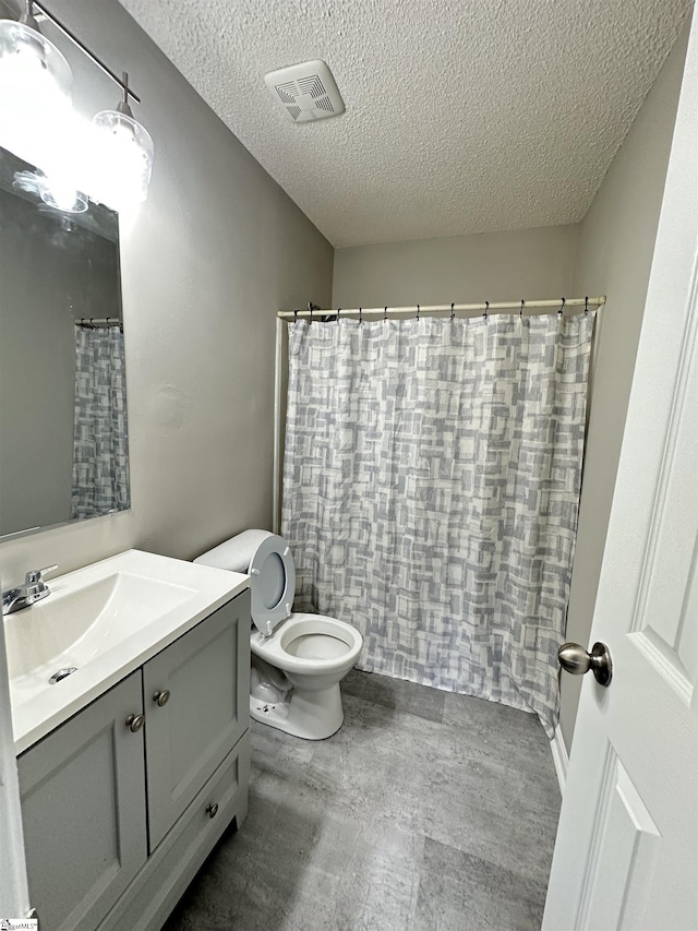 bathroom featuring vanity, a textured ceiling, toilet, and a shower with shower curtain