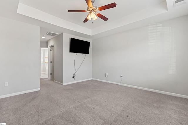 carpeted spare room featuring ceiling fan and a raised ceiling