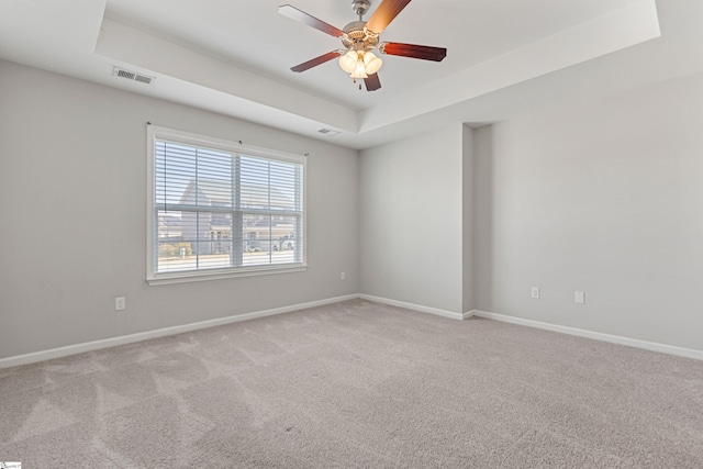 carpeted spare room featuring ceiling fan and a tray ceiling