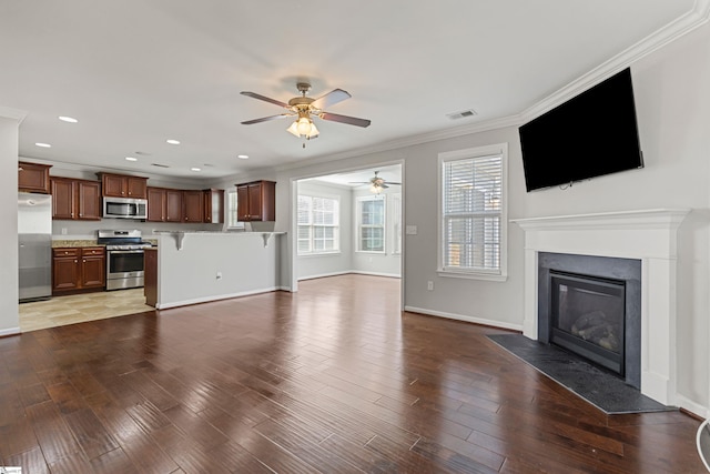 unfurnished living room with hardwood / wood-style floors, ornamental molding, and ceiling fan