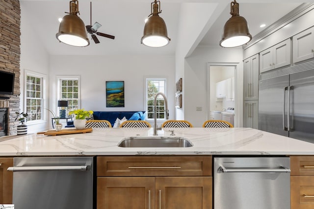 kitchen with pendant lighting, appliances with stainless steel finishes, sink, and washing machine and dryer