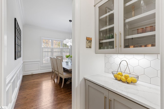 bar with gray cabinets, decorative light fixtures, decorative backsplash, ornamental molding, and light stone counters