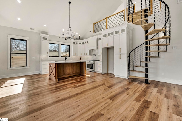 kitchen featuring premium range hood, white cabinetry, hanging light fixtures, a center island, and high end stove