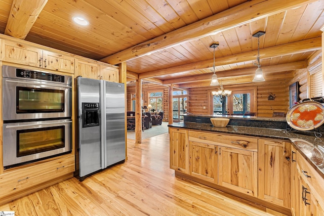 kitchen featuring light brown cabinetry, decorative light fixtures, dark stone countertops, stainless steel appliances, and beam ceiling