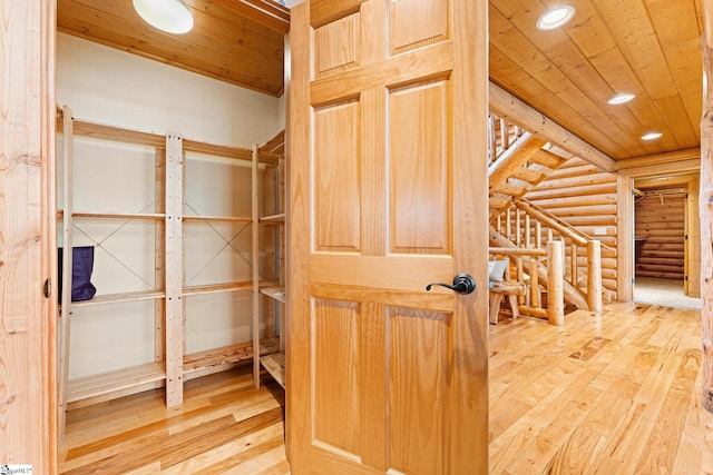 hall featuring wood-type flooring, log walls, and wood ceiling