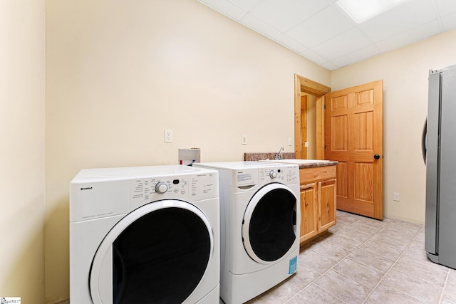 washroom with light tile patterned flooring, cabinets, sink, and washing machine and dryer