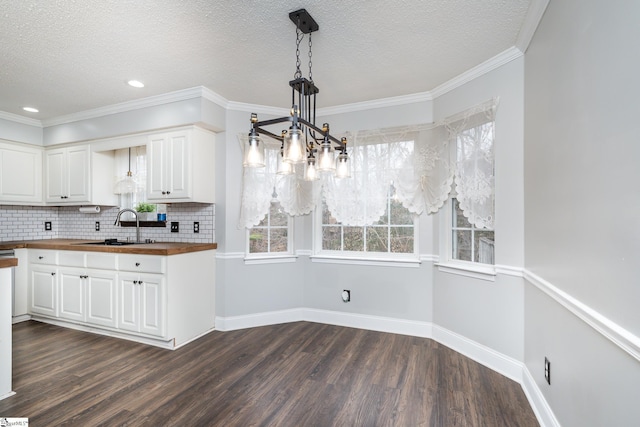 kitchen with dark hardwood / wood-style floors, butcher block countertops, white cabinetry, sink, and hanging light fixtures