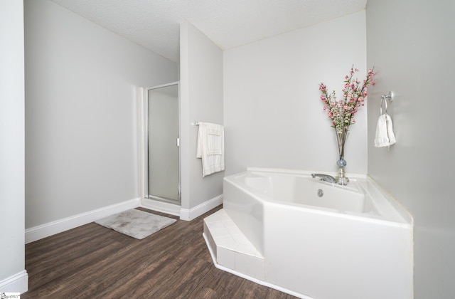 bathroom with wood-type flooring, shower with separate bathtub, and a textured ceiling