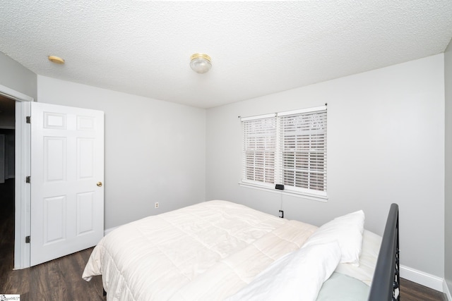 bedroom with dark hardwood / wood-style floors and a textured ceiling