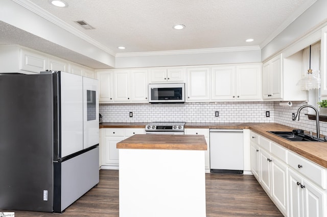 kitchen with wood counters, sink, appliances with stainless steel finishes, a kitchen island, and white cabinets