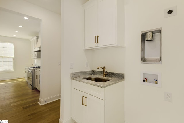 laundry area with washer hookup, sink, dark wood-type flooring, and cabinets