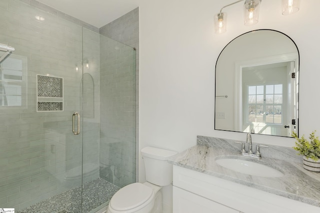 bathroom with a shower with door, vanity, and toilet