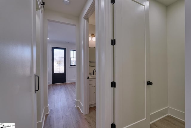 corridor featuring sink and light hardwood / wood-style floors