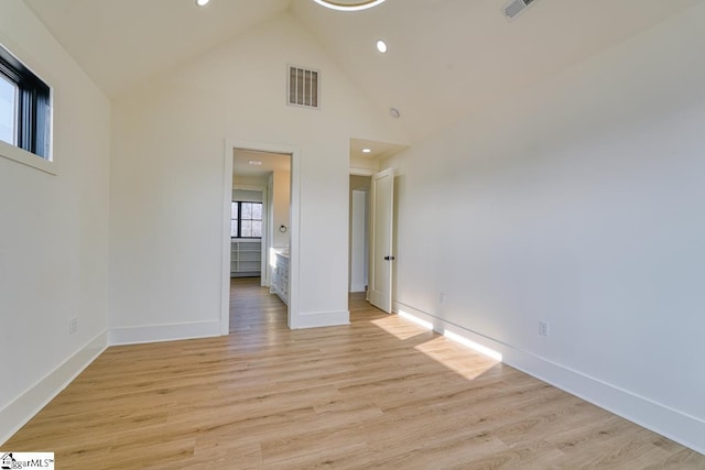 empty room with light hardwood / wood-style flooring and high vaulted ceiling