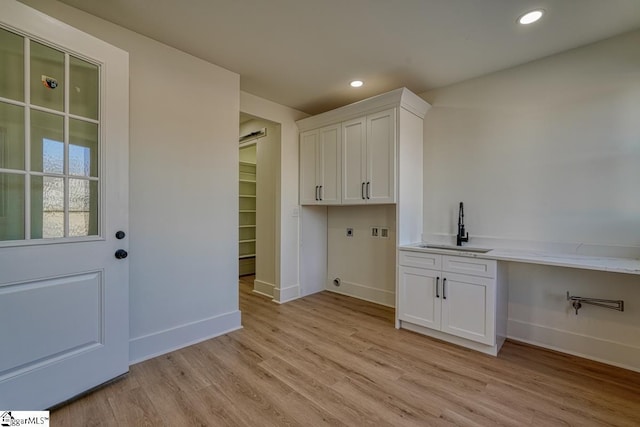 clothes washing area with sink, cabinets, light hardwood / wood-style flooring, electric dryer hookup, and a barn door