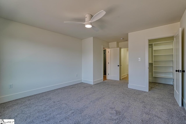 unfurnished bedroom with light carpet, a walk in closet, and ceiling fan