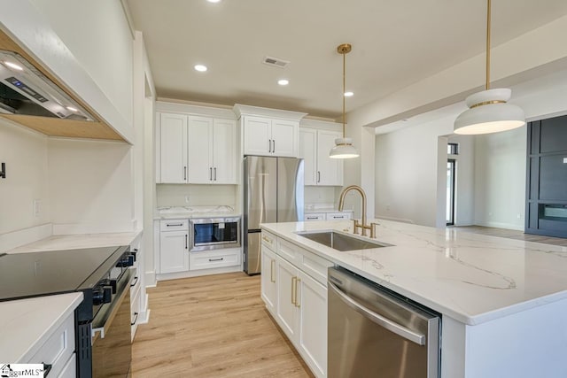 kitchen featuring sink, white cabinetry, pendant lighting, stainless steel appliances, and a kitchen island with sink