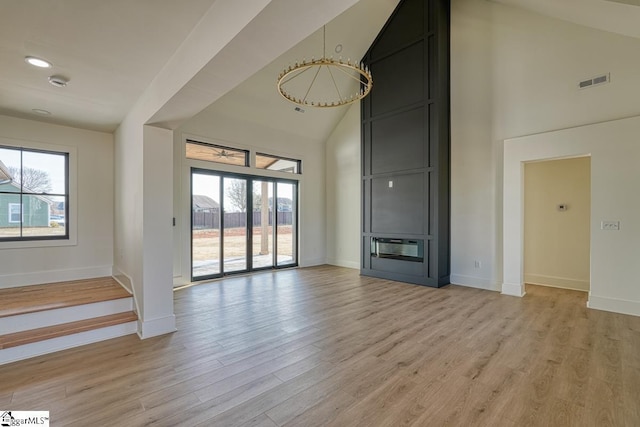 unfurnished living room featuring high vaulted ceiling and light hardwood / wood-style floors