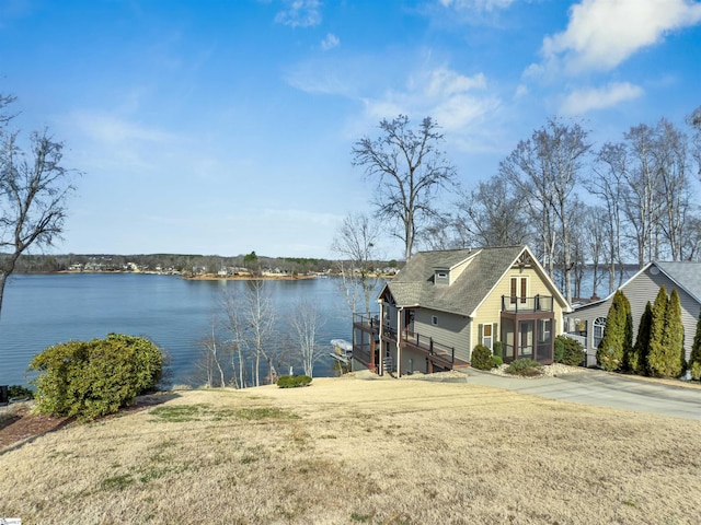 dock area with a water view, a balcony, and a lawn