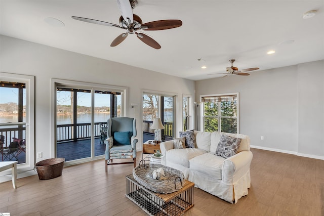 living room with a water view, a wealth of natural light, and light hardwood / wood-style floors