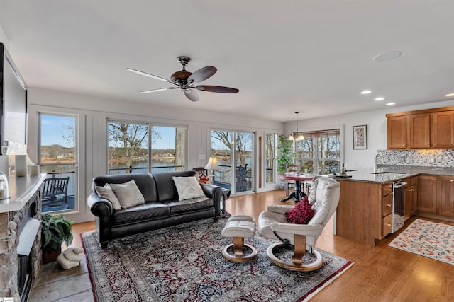 living room featuring a water view, sink, ceiling fan, and light hardwood / wood-style flooring