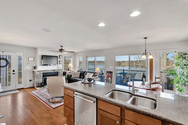 kitchen with pendant lighting, sink, dishwasher, stone counters, and a fireplace