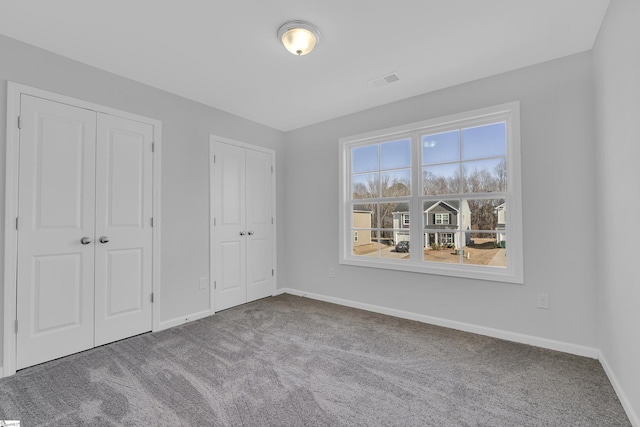 unfurnished bedroom with carpet and two closets