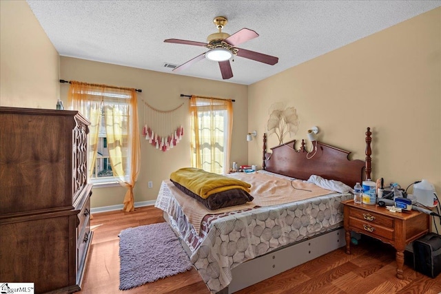 bedroom with ceiling fan, wood-type flooring, and a textured ceiling