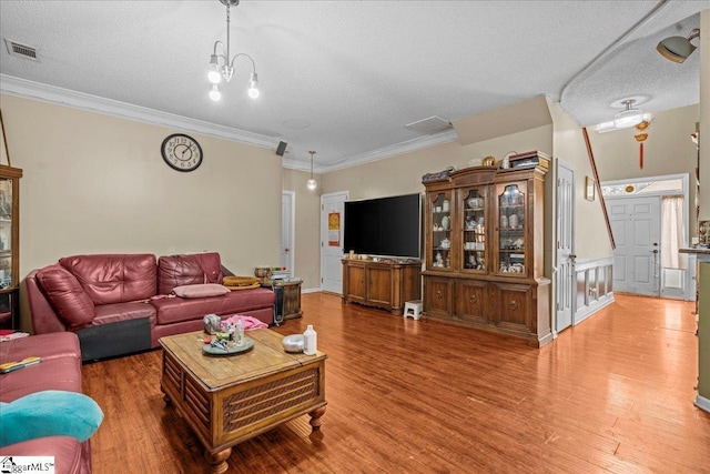 living room with wood-type flooring, crown molding, a chandelier, and a textured ceiling