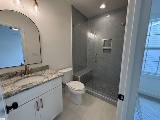 bathroom featuring an enclosed shower, vanity, and toilet