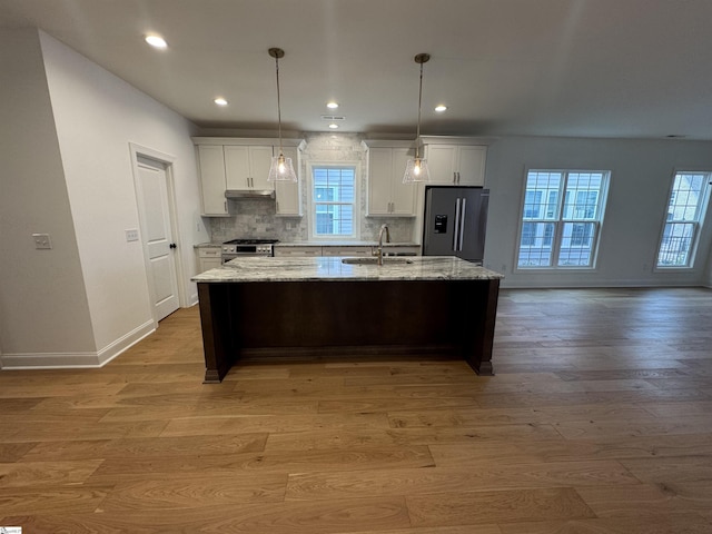 kitchen with white cabinetry, an island with sink, sink, light hardwood / wood-style floors, and stainless steel appliances