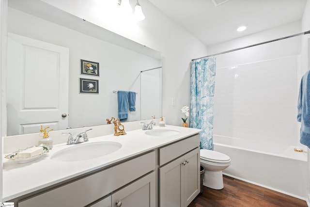 full bathroom with hardwood / wood-style flooring, vanity, shower / tub combo with curtain, and toilet