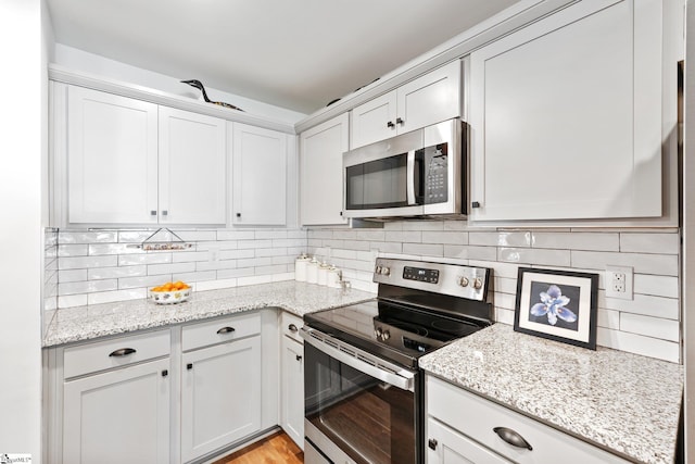 kitchen featuring light stone counters, white cabinetry, tasteful backsplash, and stainless steel appliances