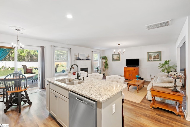 kitchen featuring pendant lighting, dishwasher, an island with sink, sink, and an inviting chandelier