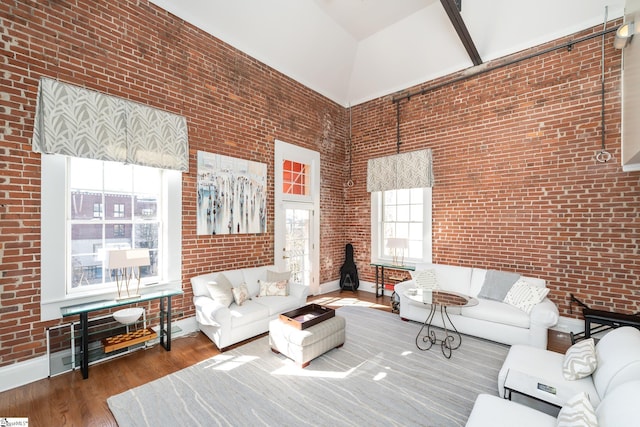 living room with wood-type flooring, brick wall, and a towering ceiling