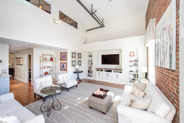 living room featuring a towering ceiling, hardwood / wood-style floors, and built in features