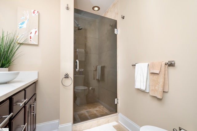 bathroom featuring a shower with door, vanity, and toilet